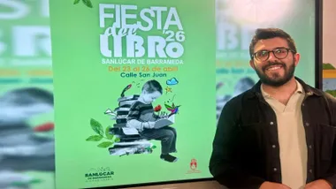 Delegado de Cultura de Sanlúcar junto al cartel, en verde y blanco, de la "Fiesta del Libro".
