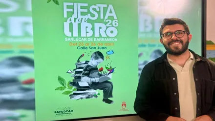 Delegado de Cultura de Sanlúcar junto al cartel, en verde y blanco, de la "Fiesta del Libro".