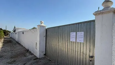 Puerta de entrada a la finca junto a un muro encalado en blanco.