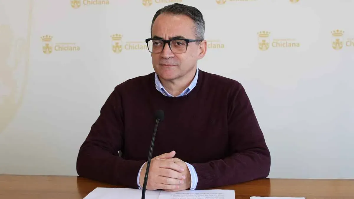 Momento de las explicaciones de Francis Salado, sentado en una mesa, lleva puesto chaleco burdeos y camisa celeste.