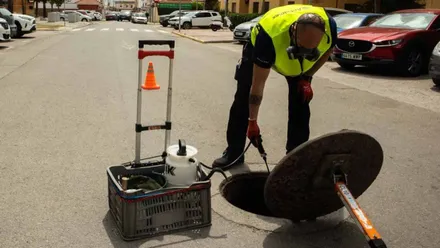 Momento en el que un operario abre una alcantarilla para fumigar.