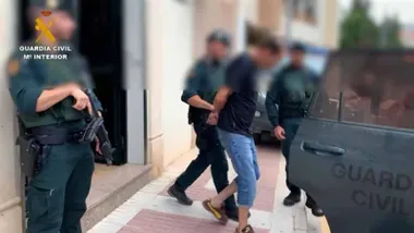 Agentes de la Guardia Civil llevando a uno de los detenidos al coche.