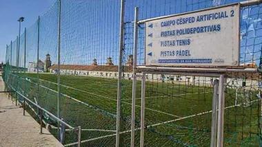 Campo de césped con valla y cartel.