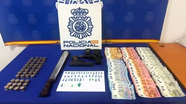 Mesa de la Policía Nacional con dinero y droga así como armas simuladas.