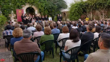 Personas sentadas en un patio viendo una exposición de temas.