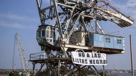 Grúa con una pancarta desplegada en la que se lee "No a las listas negras".