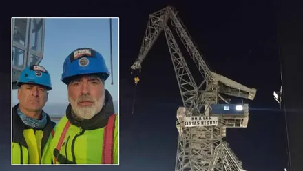 Los dos trabajadores junto a la grúa en la que se han atricherado.