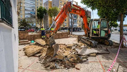 Máquina de color naranja levantando una acera.