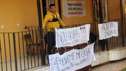 El dueño de la vivienda con pancartas reclamando su casa a los okupas.