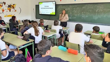 Momento en el que una clase con alumnas y alumnos atienden a la profesora.