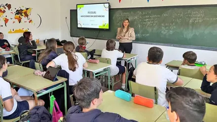 Momento en el que una clase con alumnas y alumnos atienden a la profesora.