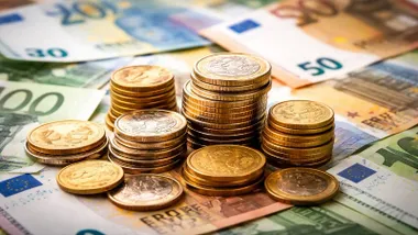 Dinero, billetes y monedas sobre una mesa.