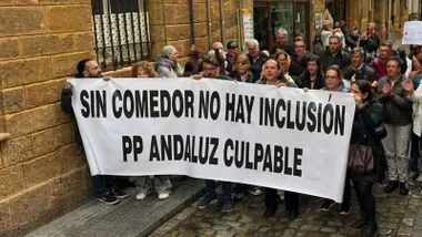 Personas manifestándose en San Fernando con una pancarta que protesta por los recortes en los comedores de los colegios.