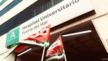 Banderolas rojas con letras blancas en la puerta del Hospital Puerta del Mar.