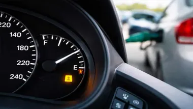 Testigo luminoso de la gasolina de un coche y aguja indicando medio depósito.