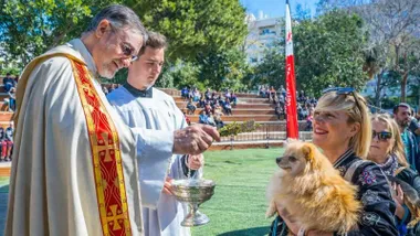 Momento en el que un sacerdote, y un monaguillo ayudándole, bendice a unos perritos.