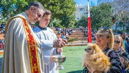 Momento en el que un sacerdote, y un monaguillo ayudándole, bendice a unos perritos.