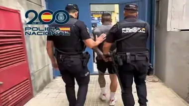 Dos policías nacionales llevan al detenido.