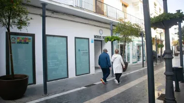 Fachada del centro de Rota donde solicitar las tarjetas, dos personas pasean por la calle.