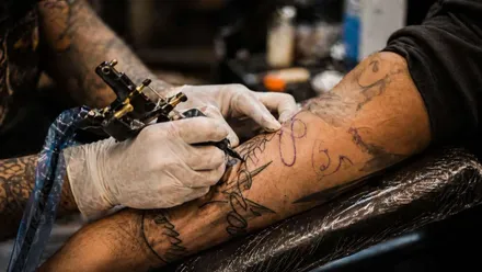 Persona tatuando el antebrazo de otra persona.