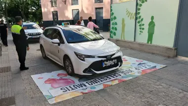 Un taxi pasa por encima de la pancarta del AMPA del COlegio Celestino Mutis. Foto: Facebook AMPA Colegio Celestino Mutis.