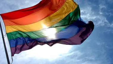 Bandera multicolor LGTBIQA+ ondeando al viento.