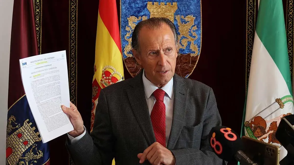 Momento en el que José María Román, de chaqueta, y delante del escudo de Chiclana, muestra el documento de las almadrabas.