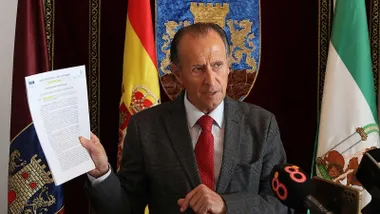Momento en el que José María Román, de chaqueta, y delante del escudo de Chiclana, muestra el documento de las almadrabas.