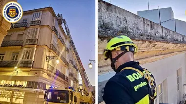 Camión de bomberos en la calle afectada y bombero trabajando en la cornisa.
