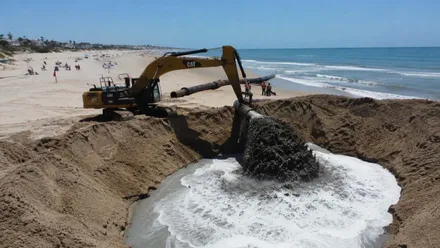 Excavadora en las tareas de aporte de arena en La Barrosa, en Chiclana.