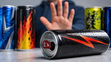 Varias latas de bebidas energéticas y una mano en actitud de rechazo.