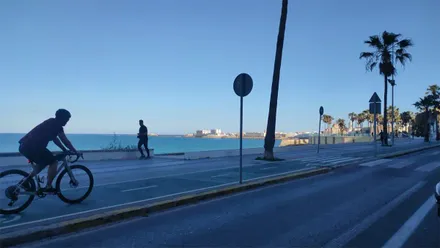 Un ciclista y un corredor hacen ejercicio en el Paseo Marítimo de Cádiz a primera hora de la mañana.
