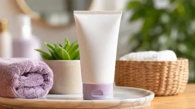Envase de una crema fotocorrectora con cuerpo blanco y tapón violeta.
