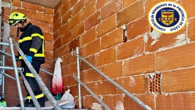 Bombero en una escalera con ladrillos vistos, es la zona del derrumbe con dos trabajadores heridos.