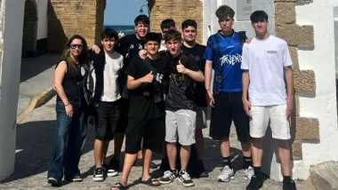 Imagen de la profesora Raquel Millán posando con varios alumnos del IES Caleta en la puerta del centro educativo, en Cádiz.