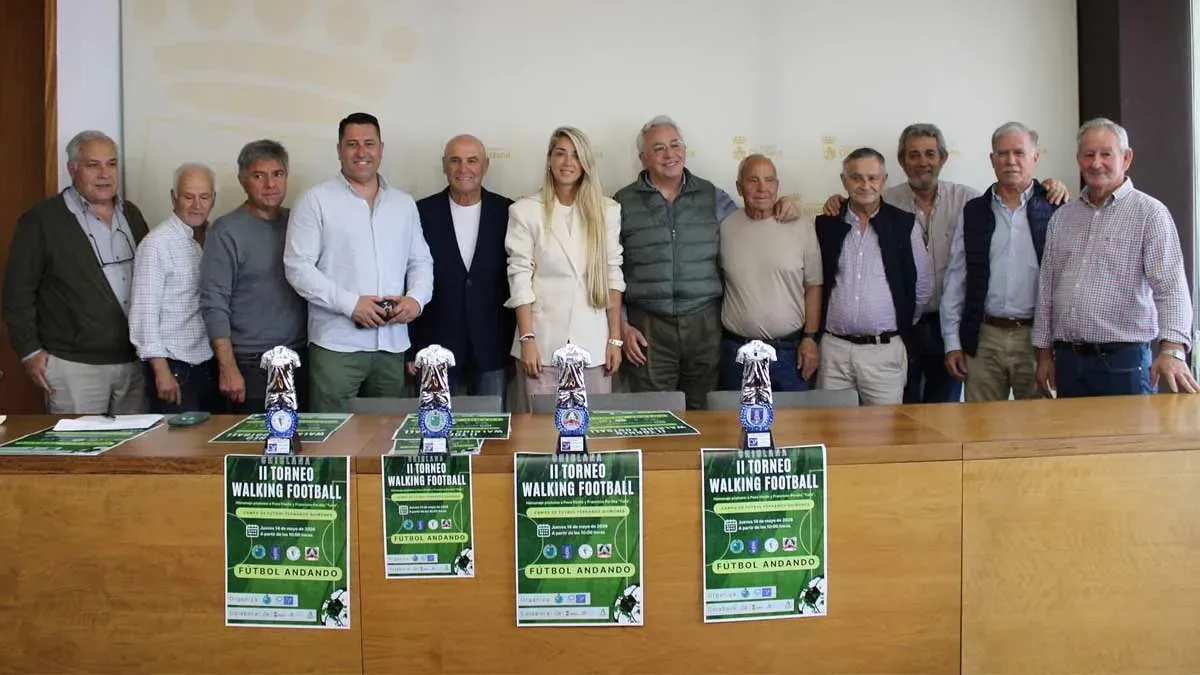 Organización y fuerzas municipales posan con el cartel del evento en Chiclana que tiene colores verdosos.