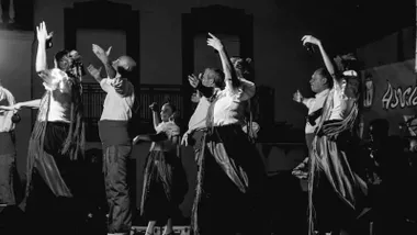 Hombre y mujeres bailando en un espectáculo de flamenco, imagen en blanco y negro.