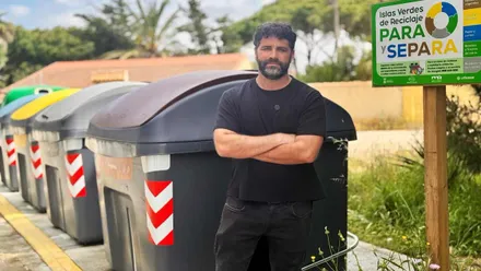 Contenedores de reciclaje, delante de ellos, con camiseta negra, Roberto Palmero.