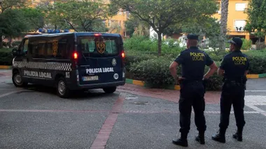 Dos agentes de la Policía Local de Los Barrios, con uniforme azul, junto a un furgón policial.