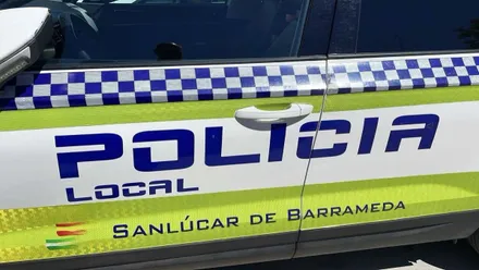 Puerta de un coche de la Policía Local de Sanlúcar, en colores blanco de fondo y azul las letras con líneas en amarillo fluorescente.