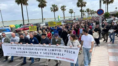 Muchas personas en manifestación, portan una pancarta de protesta contra los vertidos en el Guadalquivir.