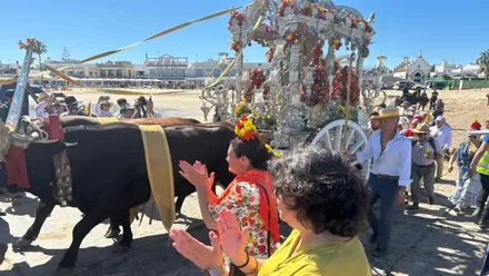 Carreta con el Simpecado por las arenas de Sanlúcar de Barrameda junto a muchas personas.