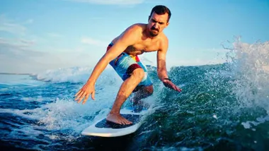 Hombre sobre una tabla surfeando.