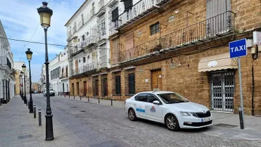 Calle de El Puerto con una parada de taxi y un coche.