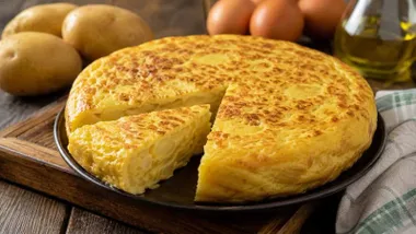 Una tortilla de patatas y una cuña cortada.