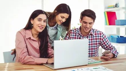 Dos chicas y un chico mirando a la pantalla de un portatil.