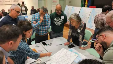Un grupo de personas está mirando unos planos orográficos y marítimos de la Bahía de Cadiz.