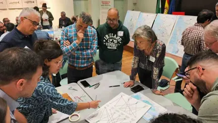 Un grupo de personas está mirando unos planos orográficos y marítimos de la Bahía de Cadiz.