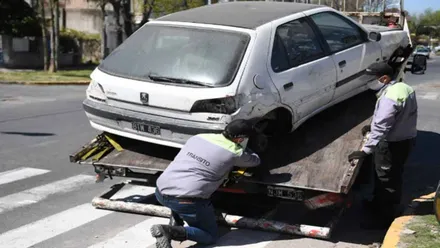 Operarios subiendo un coche abandonado a una grúa.