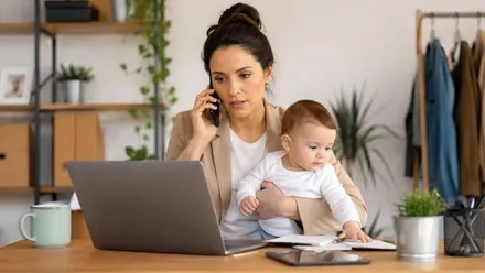 Una mujer trabajando, es autónoma, con su hijo en brazos.